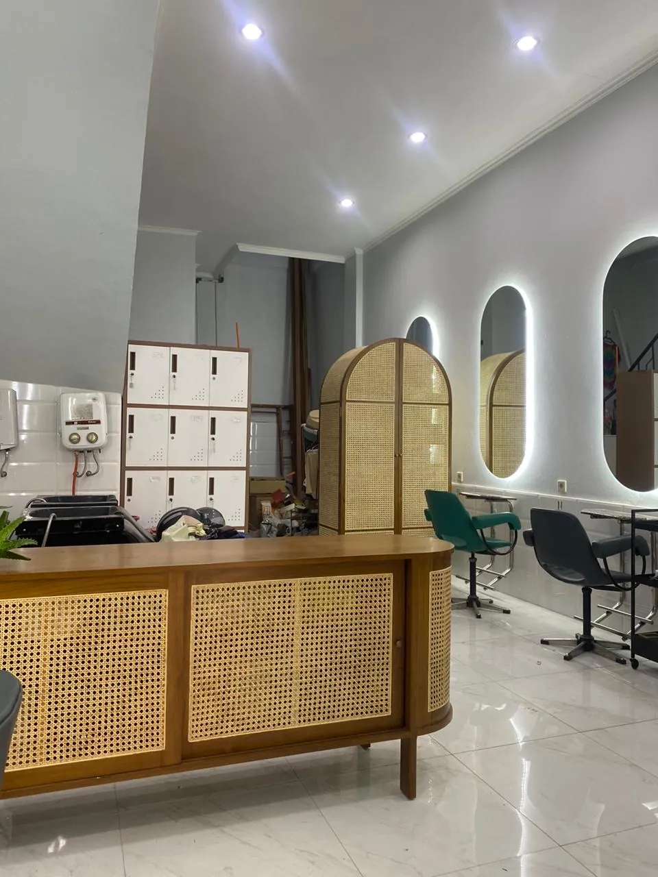 Ruang penataan rambut Yucca Salon dengan cermin lengkung berlampu dan meja rotan, Bandung
