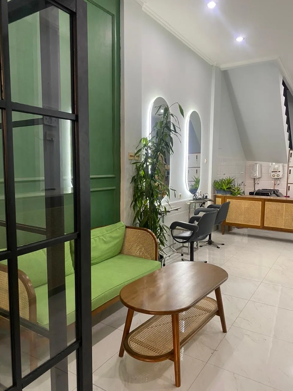 Area tunggu Yucca Salon dengan sofa rotan hijau dan tanaman, salon rambut di Jl. Gandapura Bandung