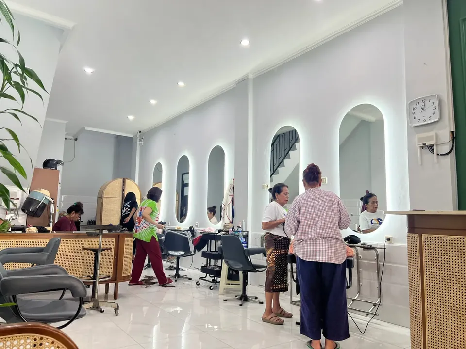 Interior Yucca Salon Bandung dengan cermin lengkung berlampu dan penata rambut melayani pelanggan walk-in